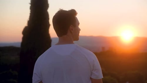 Schöner athletischer junger kaukasischer Mann genießt glücklich den Sonnenuntergang und dreht sich in Barcelona um