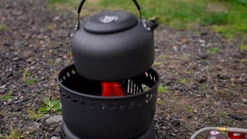 Camper Place The Kettle On The Camping Stove. - closeup shot