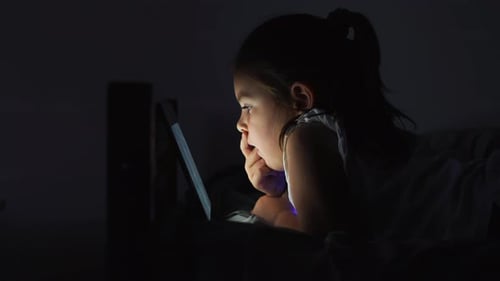 Dessins animés, réseaux sociaux ou jeux sur une tablette la nuit, les yeux d'une petite fille sont trop proches de