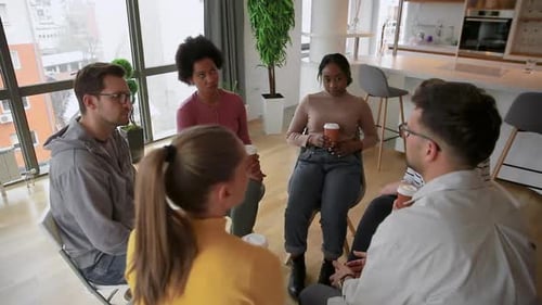 Diverse group of people sitting in circle in group therapy session.