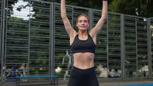 Young Fitness Woman in Activewear Doing Jumping Jacks on Stadium Outdoors