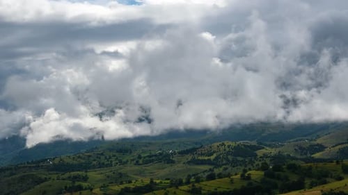 Time lapse of dramatic landscape with rolling hills and dense clouds blanketing the sky suggesting a