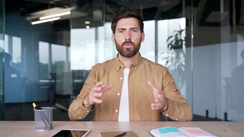 Webcam view. Confident businessman talking on a video call looking at the camera sitting at workplac