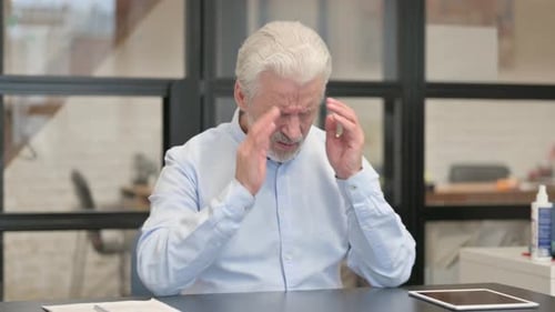 Old Businessman having Headache while Sitting in Office
