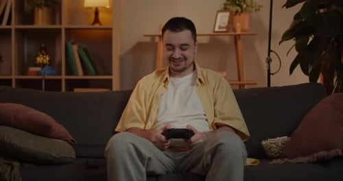 Man Smiling and Playing Video Games on Couch