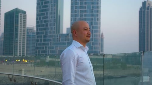 Man Standing By Glass Railing With City Background