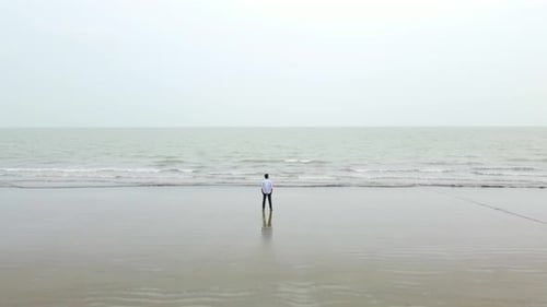 A Lonely Man Contemplates While Looking At The Sweeping View Of A Seascape. Aerial Shot