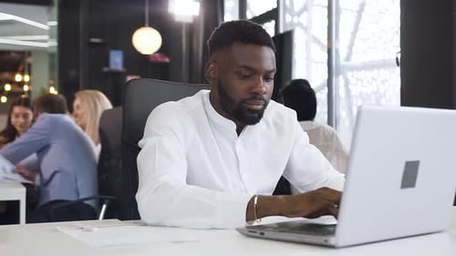Stressed Man Working on Laptop in Modern Office