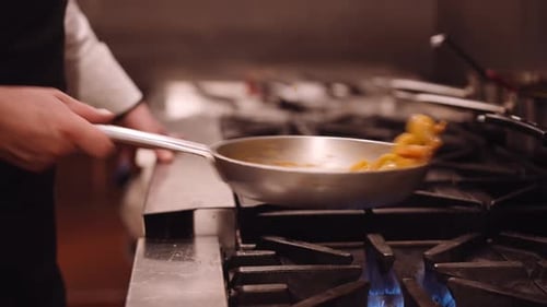 Chef Tosses Food in Pan on Stovetop