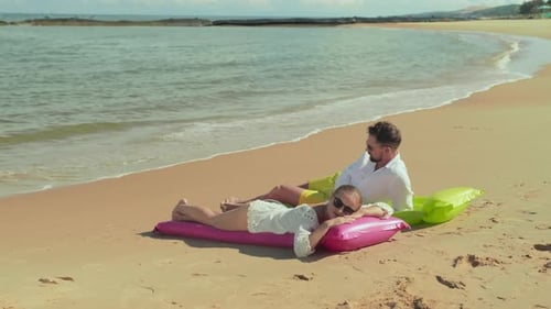 Young Restful Couple Enjoying Summer Vacation on Sandy Beach by the Sea