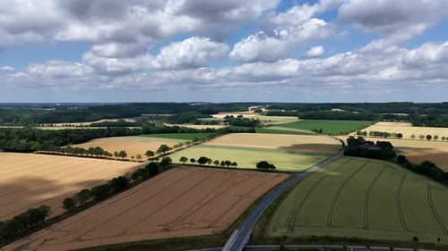 Clouds hovering over american countryside farm fields with tree-lined avenues and mountains in summe