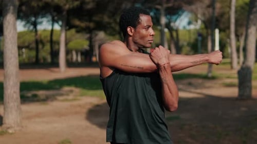 Fit Black Man Stretches in Park