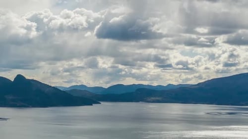 Dicke weißgraue Wolken wirbeln und bewegen sich über dem dunkelblauen Wasser des Hardangerfjords, Norwegen