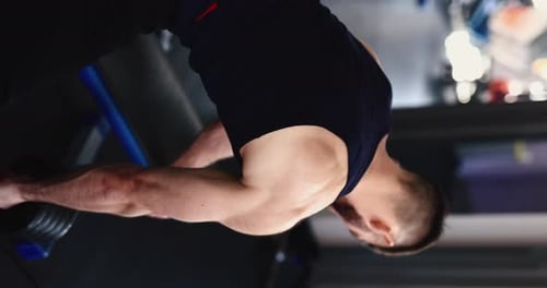 Ein Mann macht ein vertikales Video zum Hantelrudern mit einem Arm