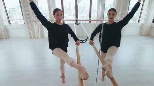 Beautiful Ballerina Exercising at the Barre in Dance Studio