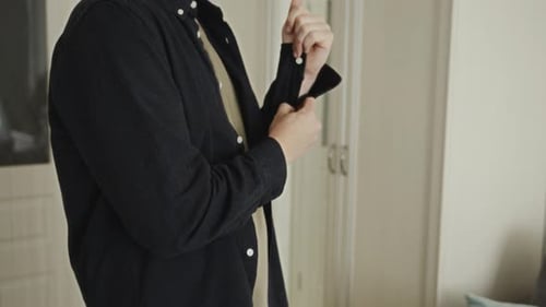 Man Prepares Rolling up Sleeves in Bright Apartment