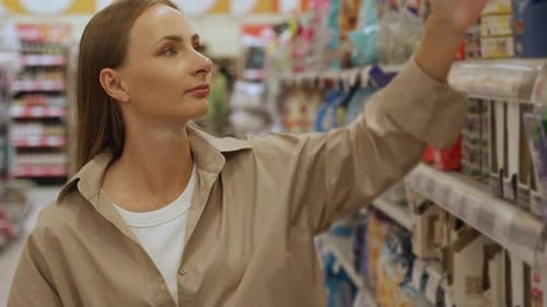 A Woman in a Tan Shirt Scans the Barcode of a Cat Food Package in a Grocery Store Aisle She is Using