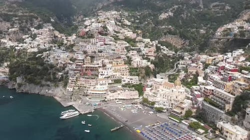 Vidéo aérienne des villas colorées de Positano, à flanc de falaise avec des bateaux sur l'océan, Italie