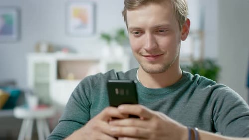 Smiling man uses phone indoors