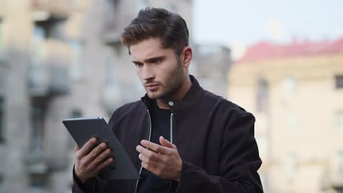 Handsome man using tablet in city has confused reaction