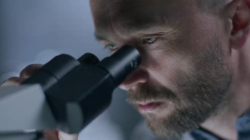 Scientist Looking Through Microscope in Bright Laboratory