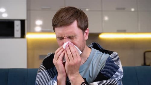 A Man in Pajamas Blows Her Nose Concept of a Person Suffering From a Cold