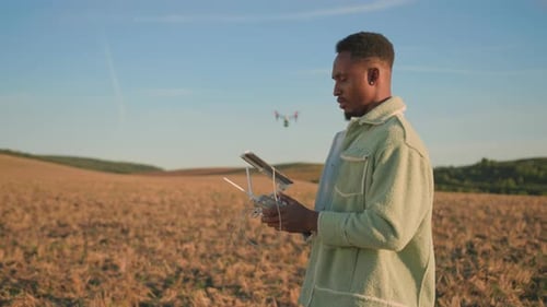 A Person Skillfully Operating a Drone in an Expansive Open Field During a Picturesque Sunset