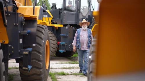 Farmer Walking Between Tractors in Rural Setting