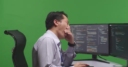 Close Up Of Developer Yawning While Write Code With Multiple Computer Screens In Green Screen Studio
