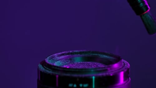Cleaning Camera Lens with Brush Under Neon Light
