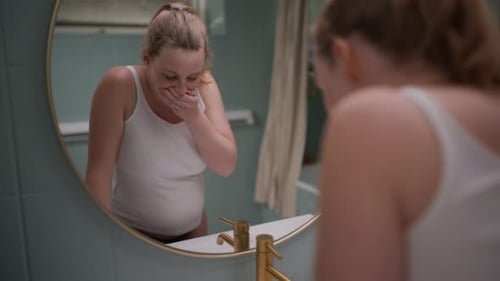 Young Woman Feeling Sick in Bathroom Leaning on Sink