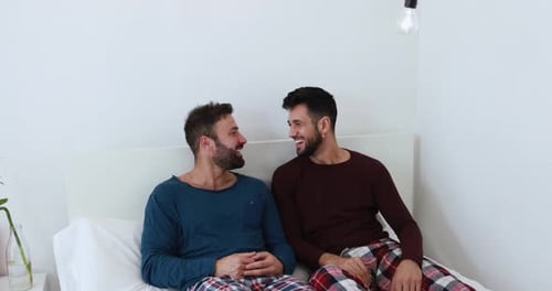 Affectionate Men Chatting in Bed, Smiling