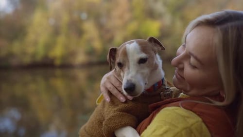 Portrait of a Smiling Young Woman Kissing a Dog in a Field