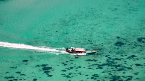 Drone shot of a small boat sailing next to the island.