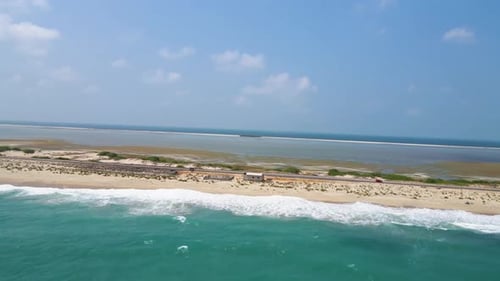 Aerial drone shot of ocean tides in the ocean beside a beach on a sunny day