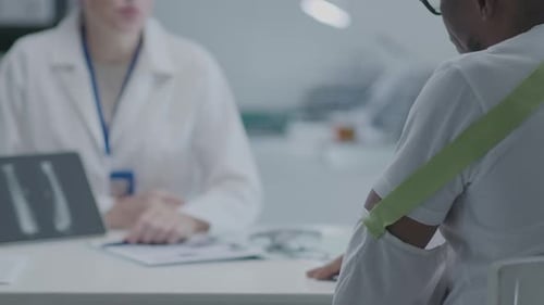 Practitioner Consulting Man with Broken Arm at the Doctors Office