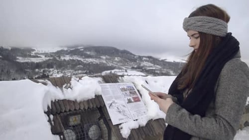 Woman Uses Phone in a Winter Mountain Landscape