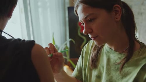 Tatuadora feminina descrevendo o design no braço do cliente