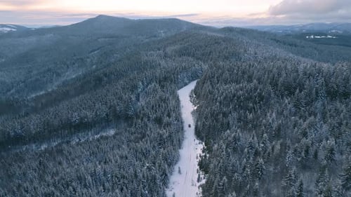 Aerial Snowy Road with Pickup Car Driving On Frozen Winter Forest