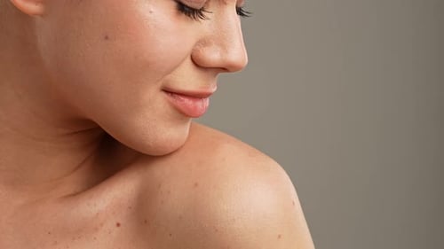 Young Woman Posing at Camera Playfully Smiling Touching Smooth Skin on the Shoulder Close Shot