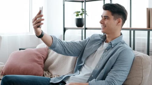 Young Man Relaxing at Home Using Mobile Phone