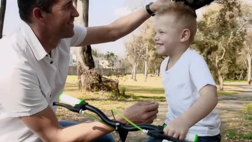 Father teaches son about bike safety on a sunny park pathway steadicam shot