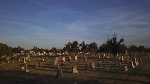 Slow aerial dolly through a graveyard at sunset