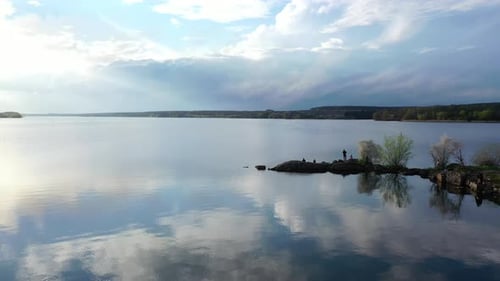 Beautiful river on nature landscape in spring. People rest near the water on stones in springtime.