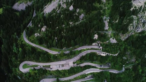 Aerial View of Winding Mountain Road Through Dense Green Forest