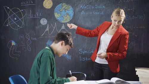 Teacher Explains Science to Student at Chalkboard