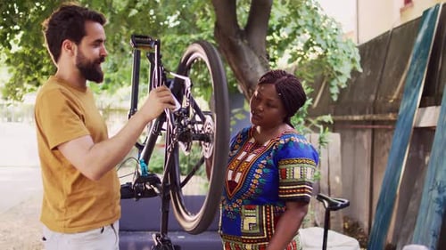 Man Repairing Bicycle with Woman Assisting Outdoors