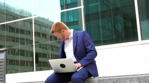 Businessman Talking to the Mobile While Working with Laptop in the City