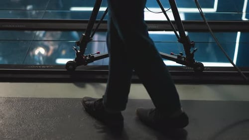 Camera Dolly on Track with Operator Leg Moving in Modern TV Studio
