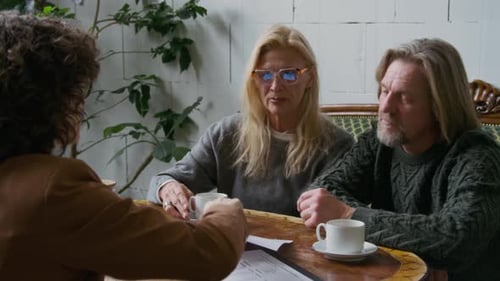 Mature Caucasian Couple Meeting with Financial Adviser in Cafe